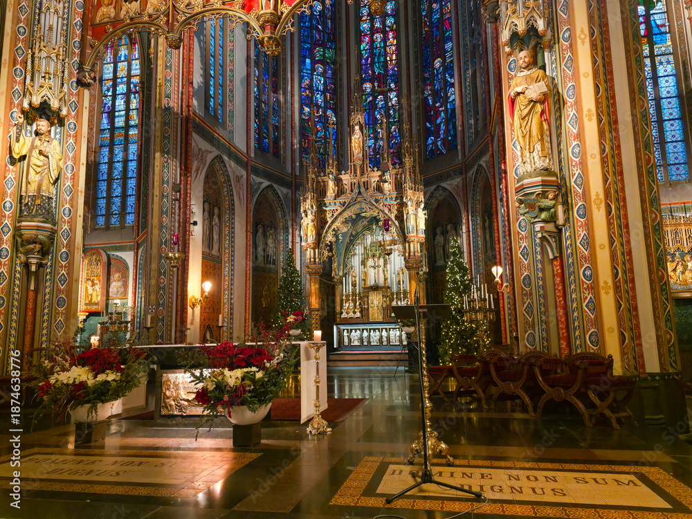 Fototapeta premium The richly decorated interior of De Krijtberg Church in Amsterdam, featuring colorful neo-Gothic details, stained glass windows, gilded statues and an ornate altar glowing with light