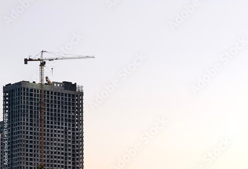 Tower crane towers over high-rise under construction at golden hour, symbolizing urban growth.