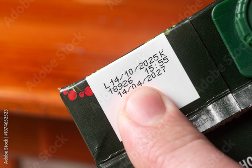 A man checks the production date and expiration date on a juice pack.