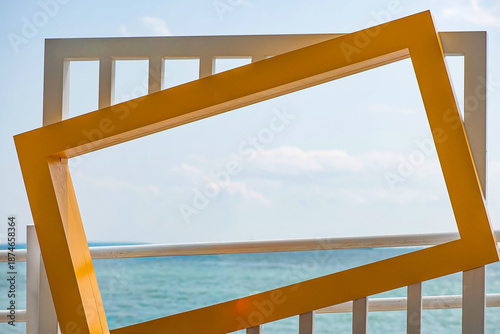 Canvas Print Empty yellow photo frame structure overlooking the blue sea