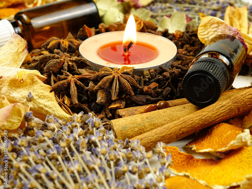 Dried herbs, flowers, bottles with essential oil, spice, orange peesl and scented candle, side view, background. Ingredients for air freshening and relaxation.
 