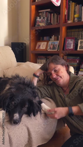 A woman is petting a black and white dog on a couch