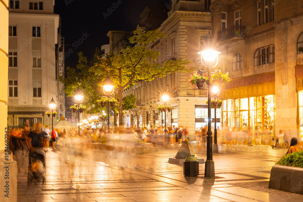 Obraz premium Warm summer evening on Knez Mihailova Street in Belgrade, with glowing lanterns, historic facades, and lively crowd of locals and tourists in motion