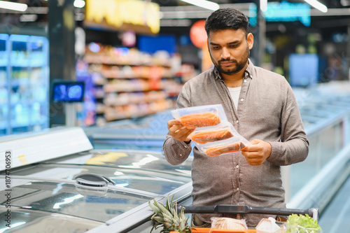 Bilde på lerret Man choosing frozen fish in supermarket freezer aisle