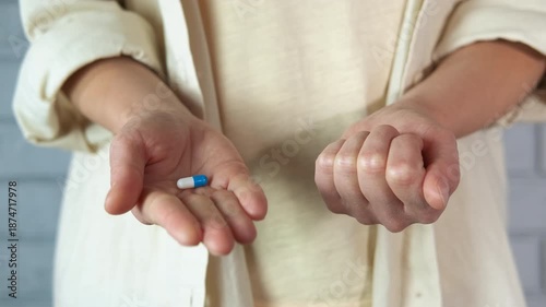 Person choosing between a blue pill and a red pill in a difficult decision. Human hands holding two pills, a blue one and a red one, symbolizing a difficult choice between two options
