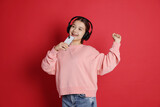 Teenage girl in headphones with smartphone on red background