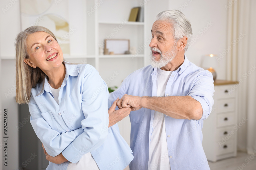 Obraz premium Happy senior couple dancing together at home