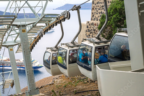 Bild auf Leinwand Cruise passengers ride the Santorini cable car down the steep cliffs towards a cruise ship docked at the Old Port of Fira, from the hilltop town of Fira