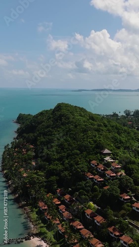 Lush palm trees lining a sandy beach with turquoise water under a bright tropical sky. Maenam, Ko Samui, Thailand.