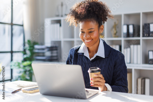 Fotografía Beautiful African american in afro hair sitting and working smiling and enjoying work while having coffee and working happily with laptop computer