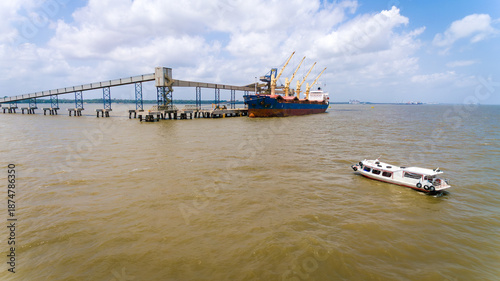 Contrast between local boat and soybean bulk carrier in Barcarena port, Amazon, Brazil