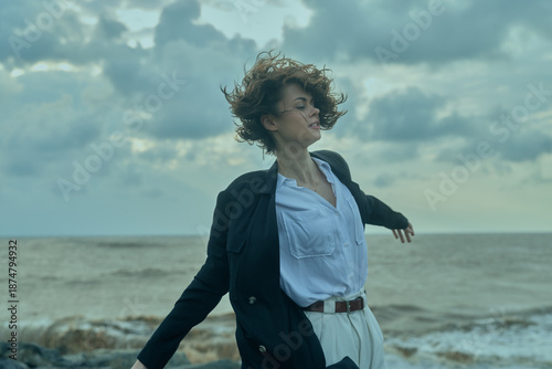Принти на полотні Wind, beach, ocean, movement, coat, shirt frame a windy scene as a woman on the