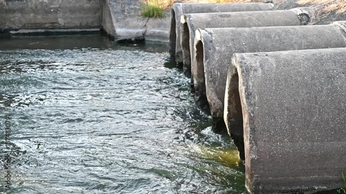 A large pipe is releasing water into a natural stream.