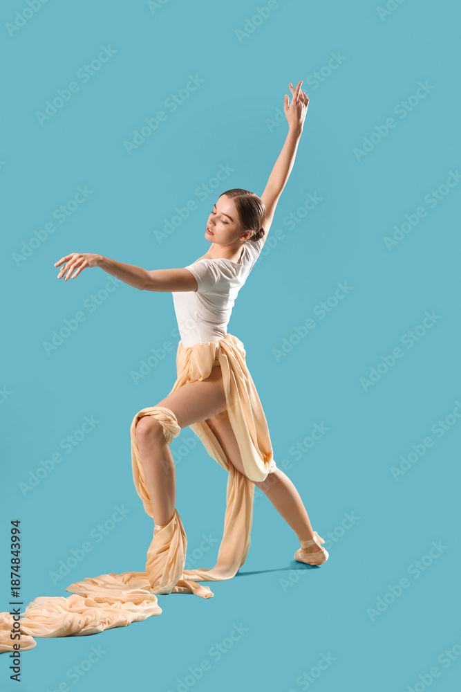 Fototapeta premium Young ballerina with fabric dancing on blue background