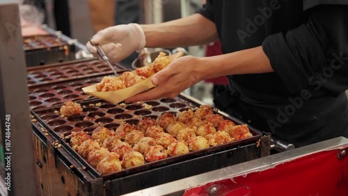 Chef picking up octopus takoyaki, a popular Japanese Osaka street food for tourists