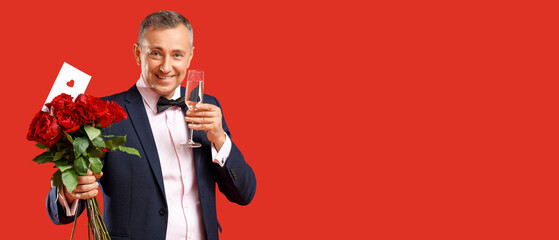 Happy mature man with bouquet of rose flowers, love letter and champagne on red background. Valentine's day celebration