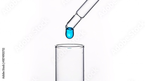 Close up of a pipette dispensing blue liquid into a test tube against white