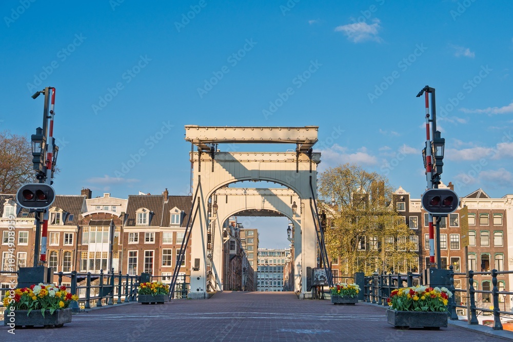 Fototapeta premium The picturesque Skinny Bridge (Magere Brug) in Amsterdam, Netherlands, a traditional Dutch drawbridge spans the Amstel River. A tourist attraction of Amsterdam. Wonderful cityscape.