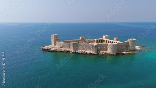 Kizkalesi, Mersin, Turkey. Maiden Castle island fortress completely surrounded by water, medieval architecture in mediterranean sea.. Aerial View, Departure of the camera
