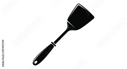 A stark black spatula against a white backdrop creating a dramatic kitchen tool silhouette
