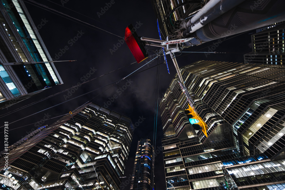 Fototapeta premium Glass towers rise sharply into the night as cables stretch overhead like the strings of a giant urban instrument