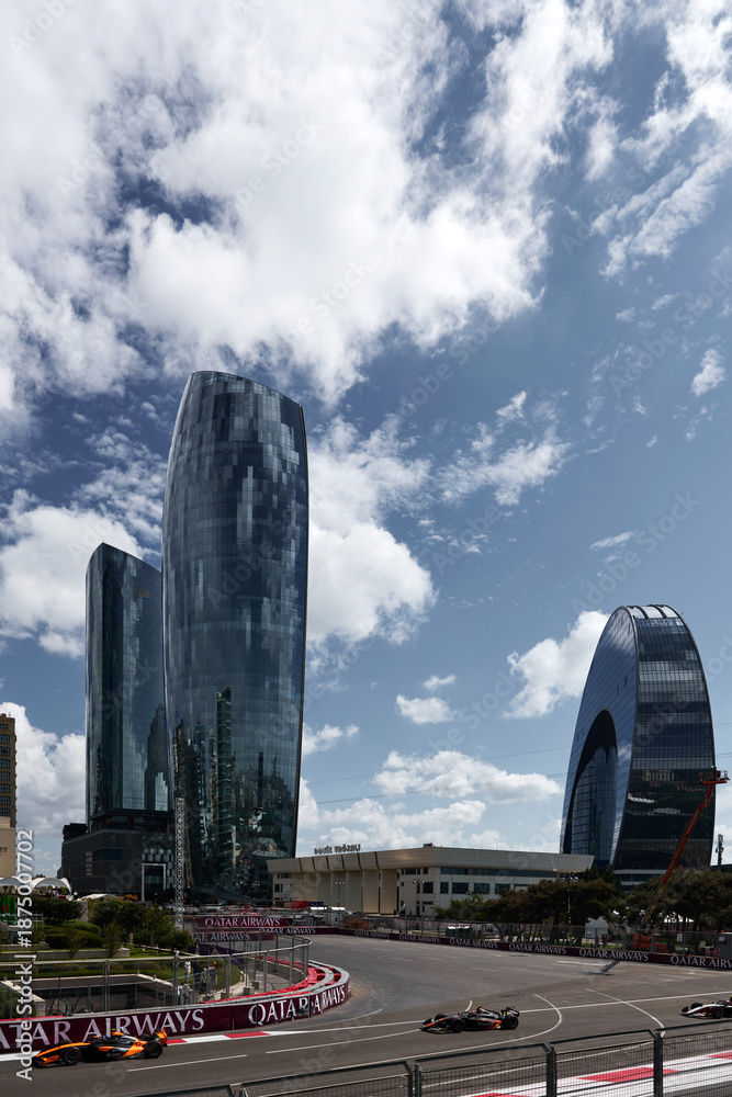 Fototapeta premium BAKU, AZERBAIJAN - SEPTEMBER 21, 2025: Baku City Circuit during the 2025 Azerbaijan Grand Prix. Modern skyscrapers and the Port Baku area contrasted with F1 cars racing on the street track