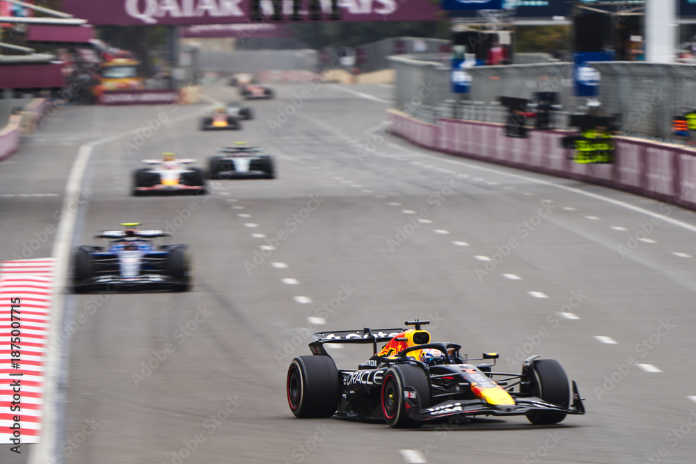Fototapeta premium BAKU, AZERBAIJAN - SEPTEMBER 21, 2025: Sergio Perez in the Oracle Red Bull Racing RB21 leads a pack of Formula 1 cars down a straight at the Baku City Circuit during the Azerbaijan Grand Prix