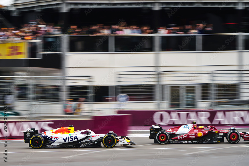 Fototapeta premium BAKU, AZERBAIJAN - SEPTEMBER 21, 2025: Liam Lawson in the Visa Cash App RB leads Lewis Hamilton's Ferrari SF-25 through the streets of Baku during the Formula 1 Azerbaijan Grand Prix