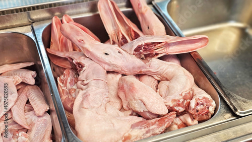Duck Meat Display: A close-up view of fresh raw duck meat presented in a stainless steel container, prepared for culinary purposes.