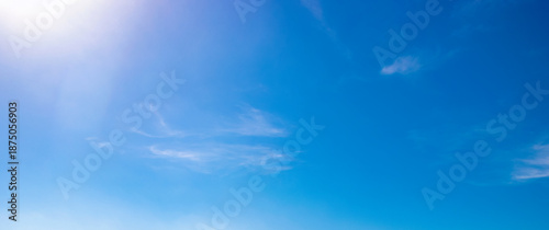Foto Clear blue sky with wispy clouds and bright sunlight in upper corner, gradient sky tones and natural cloud texture for weather background, daylight atmosphere and outdoor nature environment visuals