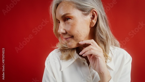 Tablou pe pânză Elderly brightly made-up woman posing against a monochrome background