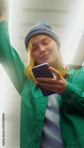 Woman smiles using smartphone in subway car
