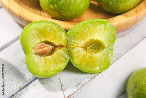 Tableau sur toile Fresh Green Sichuan Plums with Pit on White Wood Surface