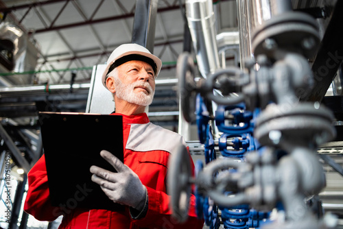 Φωτογραφία Senior engineer inspecting oil refinery pipelines