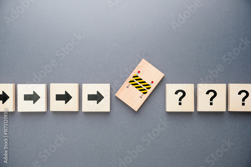 Foto Wooden arrow blocks moving forward toward a sudden obstacle and question marks,