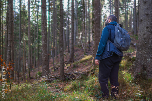 Man with backpack standing on forest hiking trail