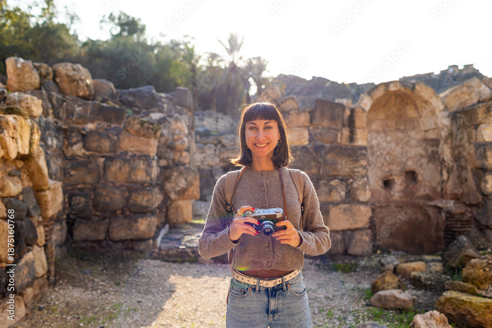 Fototapeta premium A girl with a camera. A tourist with a backpack photographs landmarks for her blog and social media.