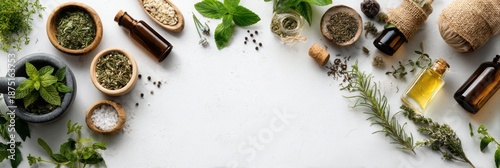 Flat lay of dried herbs, roots, and essential oil bottles on white background, ideal for alternative medicine and wellness concepts.