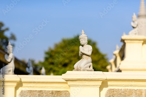 Canvastavla Kneeling guardian statue with traditional Khmer headdress and prayer gesture sits atop a pale balustrade in the Royal Palace grounds, Phnom Penh, Cambodia