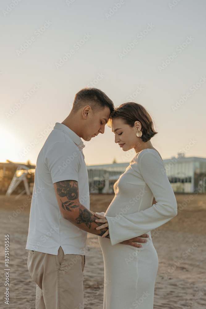 Obraz premium Happy young couple on the beach. Pregnant woman and man on a walk. Family expecting a child.