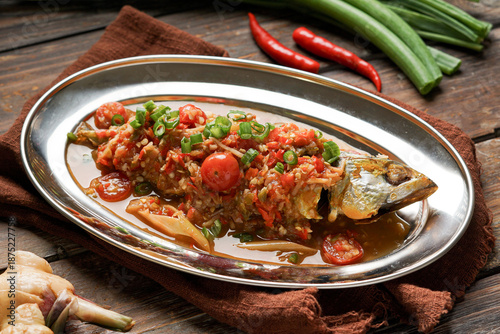 Ikan Goreng Air Asam is a traditional Malay dish featuring crispy fried fish served with fresh tamarind based dipping sauce mixed with chili onion and herbs offering a refreshing balance of sour spicy