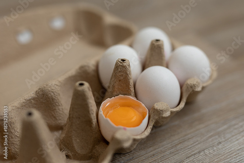 Closeup of egg carton, one egg is broken