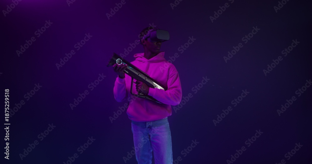Fototapeta premium A man in a virtual reality headset with a blaster in his hands in a VR studio
