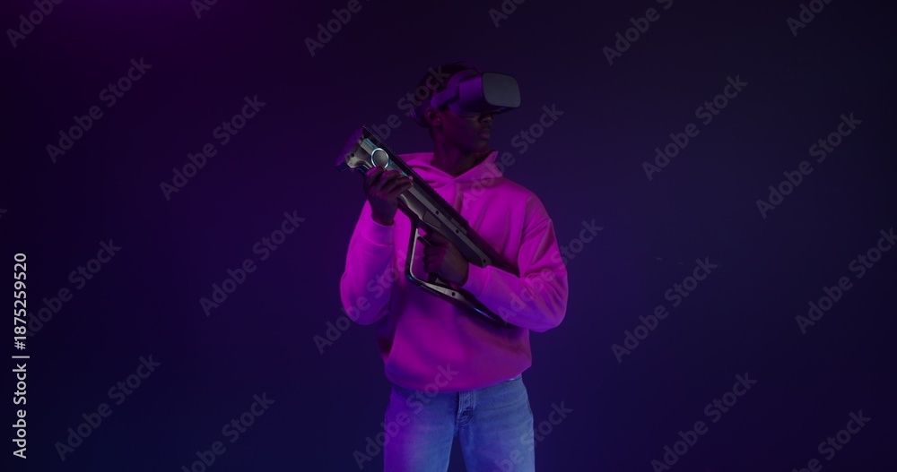 Obraz premium A man in virtual reality glasses with a game gun in his hands in a VR studio
