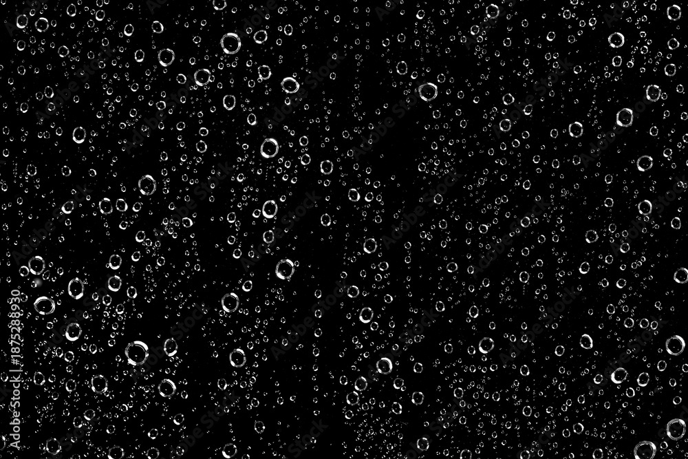 Obraz premium Thousands of water droplets (H2O) on a window pane with a black night background on a rainy day in winter. The droplets roll off the glass and flow down. High-contrast black-and-white graphic image.
