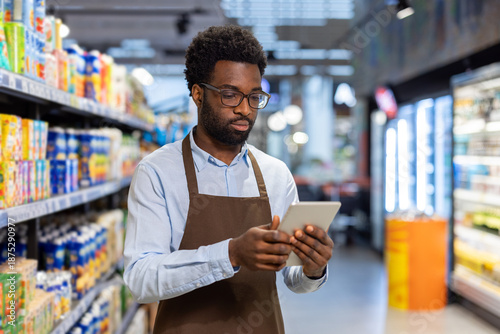 Photography African american male employee wearing an apron and glasses, using a digital tab