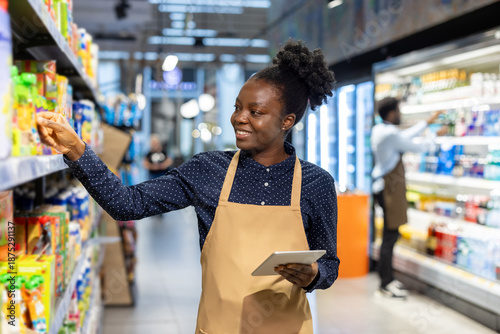Bilde på lerret Happy woman worker wearing an apron and holding a digital tablet while arranging