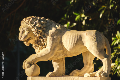 Majestic Stone Lion Statue with Paw on Sphere in Sunlit Garden