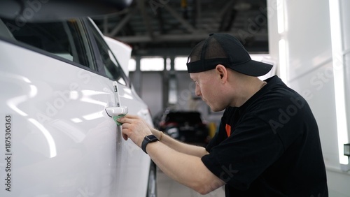 Professional car detailer applying ceramic coating to white car
