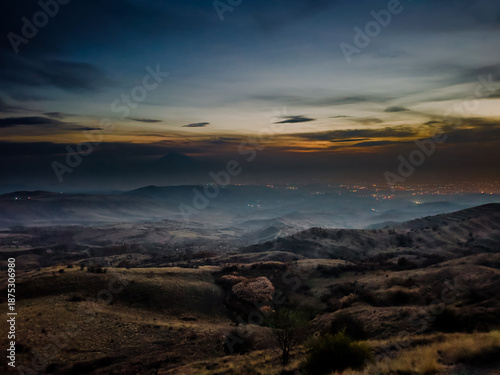 Sunset over a dry grassy field with distant mountain range under a clear gradient sky. High quality photo